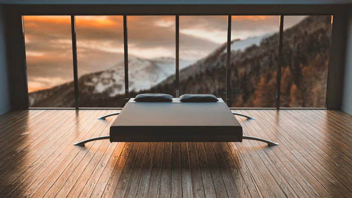 A modern minimalist bedroom with a sleek bed, set against floor-to-ceiling windows showcasing a stunning mountain view during sunset.
